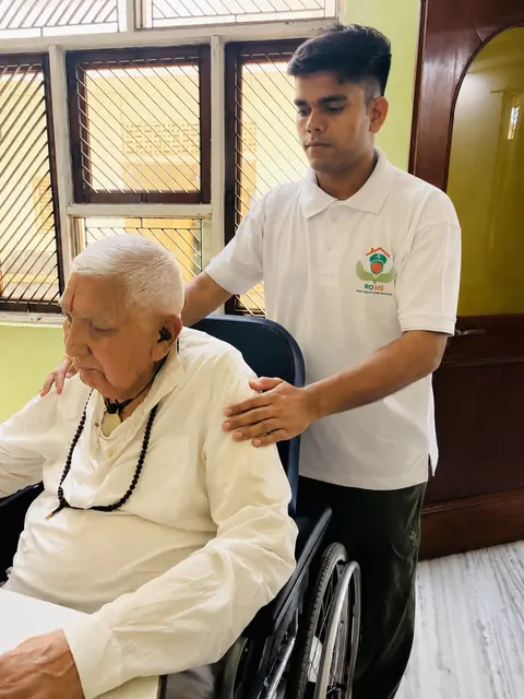 Caregiver placing a hand on the shoulder of an elderly man in a wheelchair