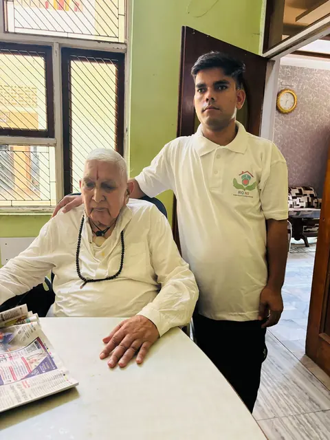 Caregiver standing behind an elderly man seated at a table