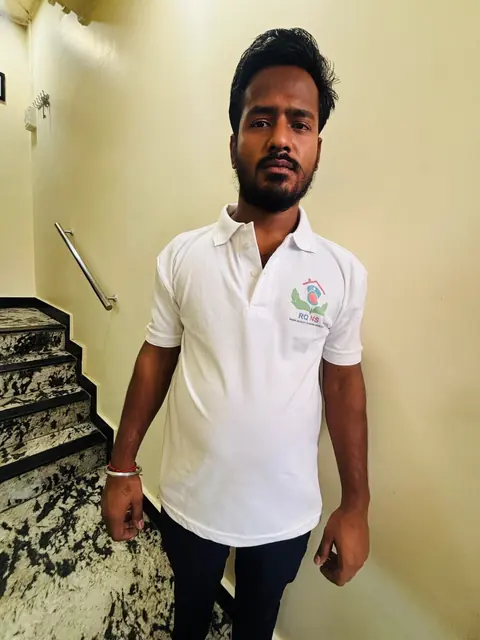 Male caregiver in a white polo standing on a staircase